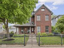 Charming brick home featuring a secure wrought iron fence and inviting front porch at 914 N College Ave, Indianapolis, IN 46202