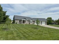 Charming brick home featuring an attached two-car garage and a well-manicured lawn at 951 N Maiellen Dr, Greenfield, IN 46140