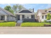 Charming home with a well-manicured lawn, gray siding, inviting front porch, and steps at 1016 Churchman Ave, Indianapolis, IN 46203