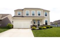Two-story tan home featuring an attached two-car garage, front yard landscaping and a covered front entryway at 10447 Pintail Ln, Indianapolis, IN 46239
