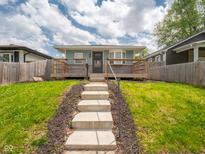 Charming blue home featuring a welcoming front porch, steps leading to the entrance, and a beautifully landscaped front yard at 1415 Lawton Ave, Indianapolis, IN 46203