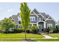 Charming gray two-story home with manicured lawn, blue door and mature tree at 1799 Hourglass Dr, Carmel, IN 46032