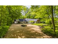 Charming brick home with a well-manicured lawn and a long, gravel driveway surrounded by lush greenery and mature trees at 535 W 93Rd St, Indianapolis, IN 46260