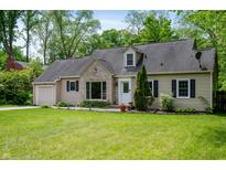 Charming home featuring a manicured lawn and stone detailing around the front picture window at 7910 N College Ave, Indianapolis, IN 46240