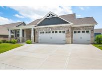 Lovely exterior features a three car garage, stone accents, brick, and well-maintained landscaping at 963 Booneway Ln, Bargersville, IN 46106
