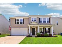 Charming two-story home with well-manicured lawn, lovely landscaping, covered front porch, and attached two-car garage at 12993 E 131St St, Fishers, IN 46037
