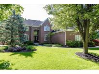 Well-maintained brick home with lush landscaping, mature trees, and a sprawling green lawn at 21218 Carlton Ct, Noblesville, IN 46062