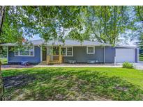 Charming single-story home with gray siding, a welcoming wooden porch, well-maintained lawn, and an attached garage at 5941 North St, Stilesville, IN 46180
