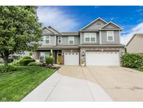Charming two-story home featuring a landscaped front yard and a three-car garage and a yellow front door at 7320 Corwin Ct, Indianapolis, IN 46259
