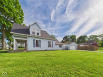 Charming blue two-story home with well-maintained lawn and detached garage on a sunny day at 814 Walnut St, Anderson, IN 46012