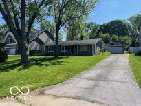 Ranch style home with a front yard and a long driveway leading to a detached garage at 825 W Auman Dr, Carmel, IN 46032