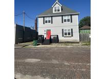 Charming two-story home featuring a striking red door, gray siding, and classic black shutters at 1128 S Pennsylvania St, Indianapolis, IN 46225