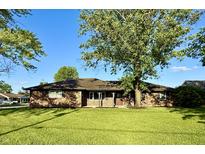 Charming brick home featuring a spacious front yard and beautiful mature trees on a sunny day at 1328 N 300 E, Anderson, IN 46012