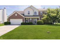 Charming two-story home featuring brick and siding exterior, manicured lawn and mature trees at 14135 Nicholas Dr, Carmel, IN 46074