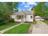 Charming single-story home with a covered front porch, lovely landscaping, and a detached garage at 376 S Arlington Ave, Indianapolis, IN 46219