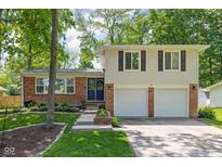 Charming home featuring a brick facade, attached two-car garage, and a well-maintained front yard with mature trees at 469 Ash Dr, Carmel, IN 46032