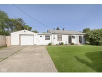 Charming home featuring a detached garage, well-kept lawn, and inviting curb appeal under a clear blue sky at 4967 Diana Dr, Indianapolis, IN 46203