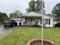 Charming single-story home with red shutters, green lawn, and beautiful landscaping, plus a car parked in the driveway at 670 Van Ave, Shelbyville, IN 46176