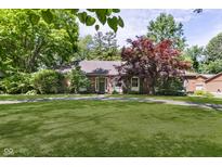 Charming single-story brick home with a well-manicured lawn and mature trees, offering great curb appeal at 7734 Hoover Rd, Indianapolis, IN 46260