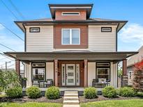 Inviting two-story home showcasing a covered front porch with seating, manicured lawn, and craftsman details at 1048 St Peter St, Indianapolis, IN 46203