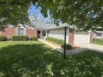 Charming single story home with lush lawn, manicured hedges and brick accents on a tree lined street at 12301 Winding Creek Cir, Indianapolis, IN 46236
