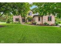 Beautiful brick home featuring a lush green lawn and mature trees providing shade at 12563 Sandstone Run, Carmel, IN 46033