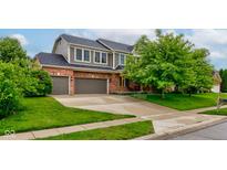 Inviting two-story home with attached two-car garage, well-manicured lawn and mature trees at 1649 Woodstock Dr, Brownsburg, IN 46112