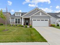 Charming home featuring a two-car garage, well-kept lawn, and stone and gray siding at 19657 Astoria Ave, Sheridan, IN 46069