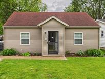Charming single-story home with tan siding, a red roof, a well-kept lawn, and a black front door at 2353 E 10Th St, Anderson, IN 46012