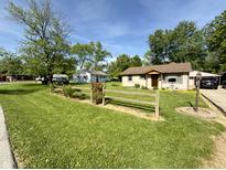 Charming single-Gathering home with a well-maintained lawn, a split rail fence, and mature shade trees at 309 Arlington Dr, Whiteland, IN 46184