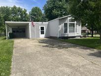 Charming one-story home featuring vinyl siding, an American flag and covered parking with a large concrete driveway at 3161 Compass Dr, Franklin, IN 46131