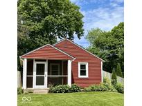 Charming red cottage with a screened-in porch, green lawn, and surrounded by mature trees at 4714 Crestview Ave, Indianapolis, IN 46205