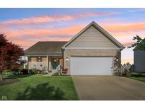 Charming single-story home with brick facade, lush lawn, tidy landscaping, and an inviting front porch at sunset at 5560 Goodwin St, Indianapolis, IN 46234