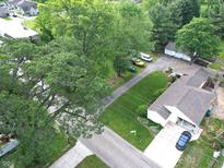 An aerial view of a home with a lush green lawn, mature trees, and a long driveway leading to a detached garage at 71 W County Road 500 S, Clayton, IN 46118