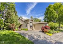 Charming home featuring mature trees, lush landscaping, and an attached two-car garage at 740 Carya Sq, Columbus, IN 47201