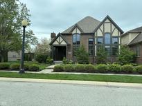 Inviting brick two-story home boasts Tudor accents, tall windows and well-manicured front lawn at 7661 Carriage House Way, Zionsville, IN 46077