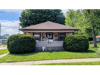 Charming single-story home with a welcoming front porch, beautiful lawn, and lush greenery at 100 N 6Th Ave, Beech Grove, IN 46107