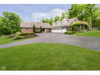 Charming brick home featuring a large driveway, three-car garage, and mature trees at 10627 Indian Lake S Blvd, Indianapolis, IN 46236