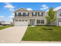 Two story home with a two car garage, light tan siding, black shutters, a green door, and lush front yard at 13887 N Hawkers Hill Dr, Camby, IN 46113