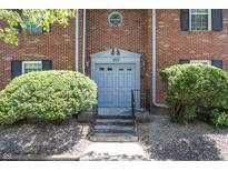 Charming brick building entrance with decorative shrubs and a light blue entryway door at 1602 Queensbridge Sq # 7, Indianapolis, IN 46219