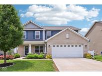Charming two-story home featuring a brick and siding exterior, attached garage, and a well-maintained front yard at 220 Sawdust Trl, Greenfield, IN 46140