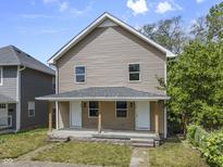 Two-story home featuring a covered front porch with sturdy wood pillars at 418 Harlan St, Indianapolis, IN 46201
