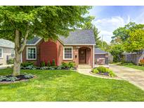 Charming brick home featuring a well-manicured lawn, mature tree, and delightful landscaping at 5809 N Illinois St, Indianapolis, IN 46208