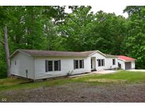 Charming single-story home with white siding, black shutters, and a well-maintained lawn surrounded by lush trees at 6538 N Tutterow Rd, Monrovia, IN 46157