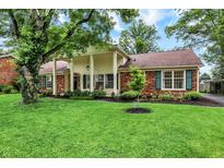 Well-maintained home with manicured lawn, mature trees and brick and wood trim at 6605 Grosvenor Pl, Indianapolis, IN 46220