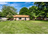 Charming brick ranch home with a large front yard and mature trees at 7110 N Layman Ave, Indianapolis, IN 46250