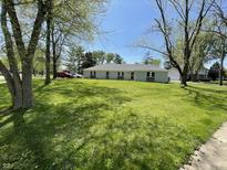 Ranch style home with a well-manicured front yard and mature trees offers great curb appeal at 7731 Scarborough S Blvd, Indianapolis, IN 46256
