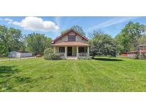 Charming two-story home features a cozy front porch and a well-manicured lawn on a sunny day at 102 N Whitcomb Ave, Indianapolis, IN 46224
