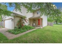 Charming two-story home featuring a well-manicured lawn, rose bushes, and a bright red front door at 1452 Brookside N Ct, Columbus, IN 47201