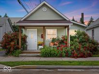 Charming home featuring a covered front porch surrounded by vibrant landscaping and red roses at 334 E Pennsylvania St, Shelbyville, IN 46176